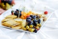 Different kinds of wine snacks: cheeses, crackers, fruits and olives on white table Royalty Free Stock Photo