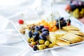 Different kinds of wine snacks: cheeses, crackers, fruits and olives on white table Royalty Free Stock Photo