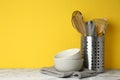 Different kitchen utensils on marble table against yellow background Royalty Free Stock Photo