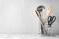 Different kitchen utensils on table against light background