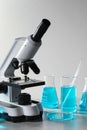 Different laboratory glassware with light blue liquid and microscope on table Royalty Free Stock Photo
