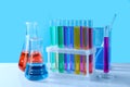 Different laboratory glassware with colorful liquids on white table against light blue background Royalty Free Stock Photo