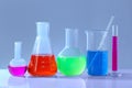 Different laboratory glassware with colorful liquids on white table against grey background Royalty Free Stock Photo