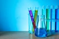 Different laboratory glassware with colorful liquids on wooden table against light blue background. Space for text Royalty Free Stock Photo