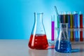 Different laboratory glassware with colorful liquids on wooden table against light blue background. Space for text Royalty Free Stock Photo