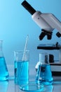Different laboratory glassware with blue liquid and microscope on table Royalty Free Stock Photo