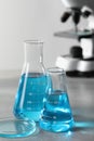 Different laboratory glassware with light blue liquid on table Royalty Free Stock Photo