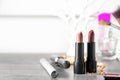 Different lipsticks and other cosmetics on grey table
