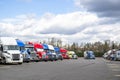 Different makes and models of the big rig semi trucks and semi trailers standing in row on the long truck stop parking lot at Royalty Free Stock Photo