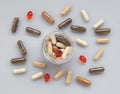 Different medicinal capsule spill out of a glass jar on a light Royalty Free Stock Photo