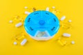 Different medicines, omega capsules, for one week and a blue pills box on yellow background Royalty Free Stock Photo