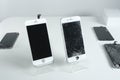 Different modern mobile phones with broken screen on white table Royalty Free Stock Photo