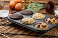 Different Muffins in bakeware or muffin pan on broun wooden background. Basic muffin recipe. Homemade muffins for breakfast or des