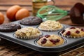 Different Muffins in bakeware or muffin pan on broun wooden background. Basic muffin recipe. Homemade muffins for breakfast or des