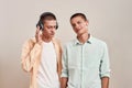 Two young caucasian twin brothers in casual wear listening music in headphones and wireless earphones, while standing Royalty Free Stock Photo