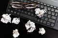Different objects on black office desk. Modern black office desk table with laptop keyboard, glasses, crumpled paper balls
