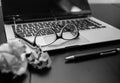 Different objects on black office desk. Modern black office desk table with laptop keyboard, pen, crumpled paper balls, glasses