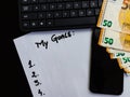 Different objects on black office desk. Paper with my goals, phone, euro money