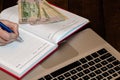 Different objects on wooden office desk. Modern wooden office desk table with laptop keyboard, dollars money, office agenda. Royalty Free Stock Photo