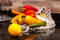 Different organic fruits and vegetables in avoska on the kitchen table. Banana, lemon, carrot, cucumber and pepper in string bag.