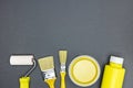 Different paintbrushes with paint rollers and cans of yellow paint on dark background Royalty Free Stock Photo