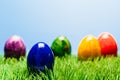 Different painted easter eggs in grass, blue background