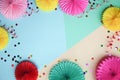 Different paper flowers and confetti on color table top view. Festive or party background. Flat lay style. Copy space for text. Bi Royalty Free Stock Photo