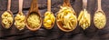 Different pasta types in wooden spoons on the table. Top view.