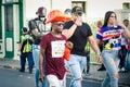 Different people in mottled costumes pass by city street at dominican carnival