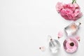 Different perfume bottles and flowers on background, top view