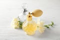 Different perfume bottles and flowers on white background Royalty Free Stock Photo