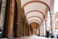 Different perspective of bologna porches with cars and people walking during summer day, an architecture landmark and symbol of