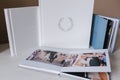 Different photobooks and photoboxes on white wooden table. Textile and leather