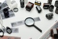 Different photographic films, scissors and magnifying glass on white background