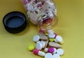 Different pills from a bottle on a yellow background Royalty Free Stock Photo