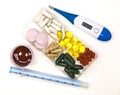 Different pills, medications in the box for drugs with medicine with a syringe and with thermometer on white background closeup.