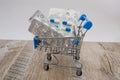 Different pills in a shopping cart on a wooden table. Side view. Royalty Free Stock Photo