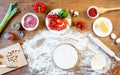 Different pizza ingredients, vegetables and dough on wooden tabletop