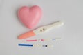 Different positive pregnancy tests with a pink heart Royalty Free Stock Photo