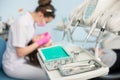 Different professional dental instruments, on the blurred background dentist is treating patient in dental office Royalty Free Stock Photo