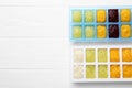 Different purees in ice cube trays ready for freezing on white wooden table, flat lay. Space for text Royalty Free Stock Photo