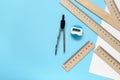 Different rulers, pencil sharpener and compass on light blue background, flat lay. Space for text