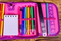 Different school stationeries (pens, pencils, notepad, ruler and protractor) in a pink pencil box. Top view Royalty Free Stock Photo