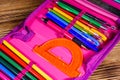 Different school stationeries (pens, pencils, ruler and protractor) in a pink pencil box Royalty Free Stock Photo