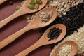 Different seeds in wooden spoons on a surface of different seeds and brown background Royalty Free Stock Photo