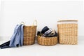 Different shape of wicker basket full of laundry clothes in clean white wall background inside bedroom. Royalty Free Stock Photo