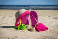 Different shapes made of sand, children toys for playing and accessories for relax. Straw hat, slippers and towel. Summer time on