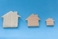 Different Size Of Houses Arranged In Row on blue background. Three differently sized cardboard models of houses. Rent, purchase,