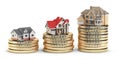Different size houses vith different value on stacks of coins. C
