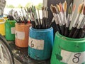 Different sized artists paint brushes lined up in pots